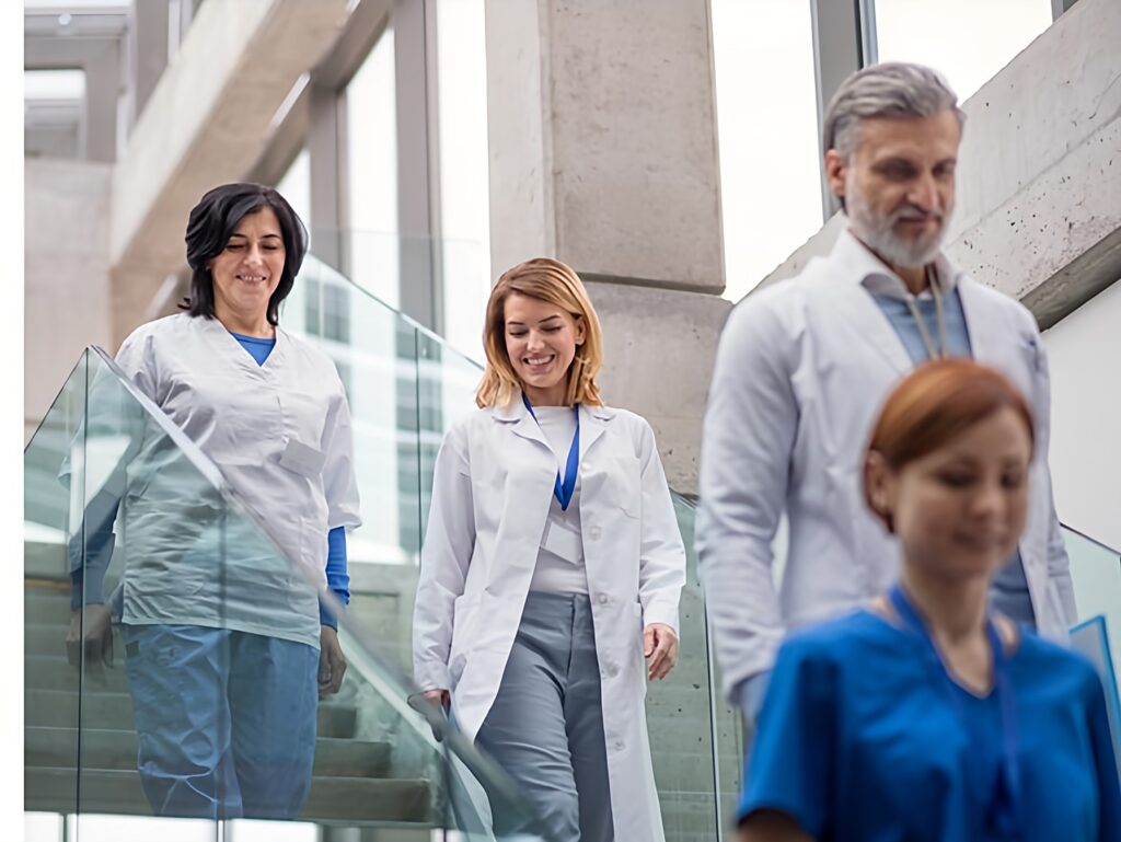 WEBSITE-DESIGN-MEDICAL-BUSINESSES showing Four medical staff in white coats and scrubs walking in a hospital building